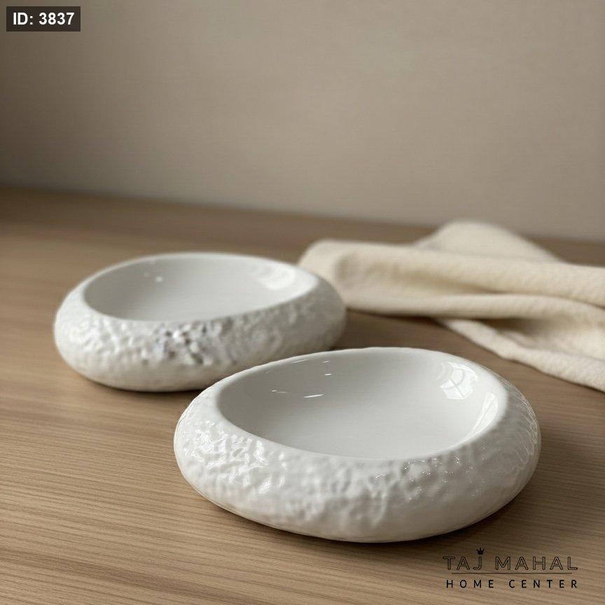 A set of two white oval serving plates with a decorative outer rim
