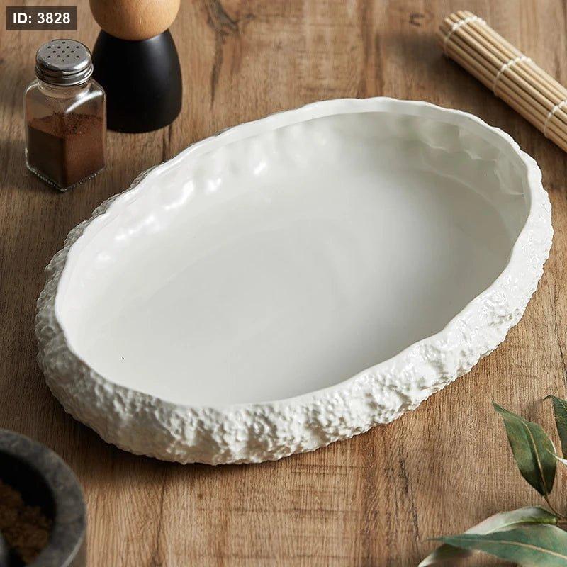 A set of white ceramic oval serving dishes with rock-textured edges