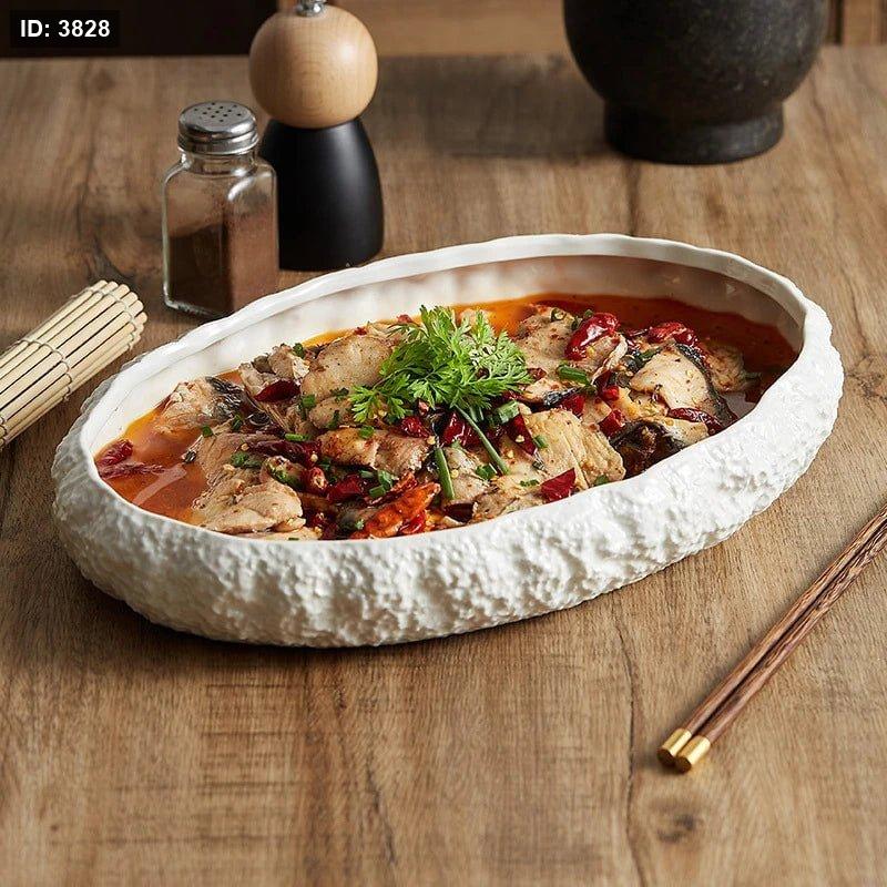 A set of white ceramic oval serving dishes with rock-textured edges