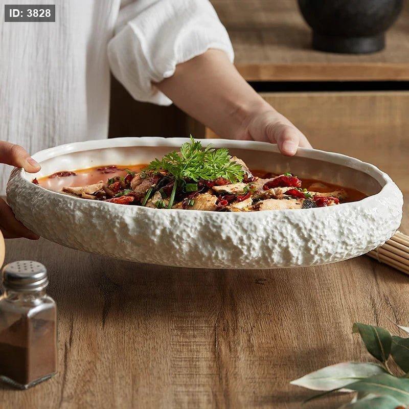A set of white ceramic oval serving dishes with rock-textured edges