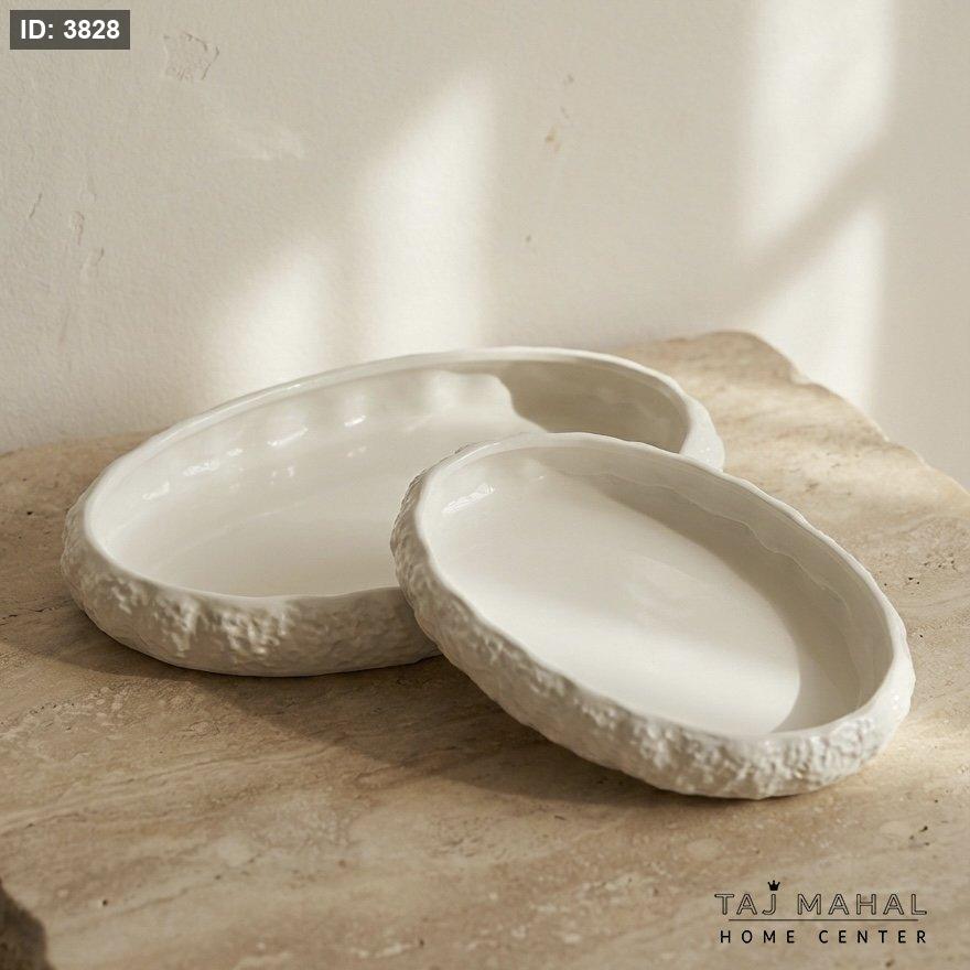 A set of white ceramic oval serving dishes with rock-textured edges