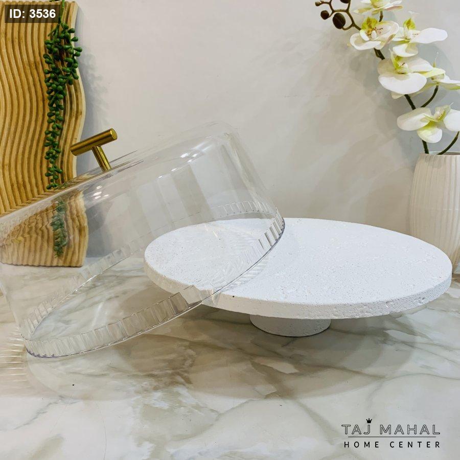 Serving plate with a white base, a transparent glass lid, and a gold handle
