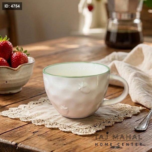 White ceramic mug with strawberry patterns and a green rim